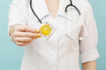 woman doctor holding yellow condom in front of her